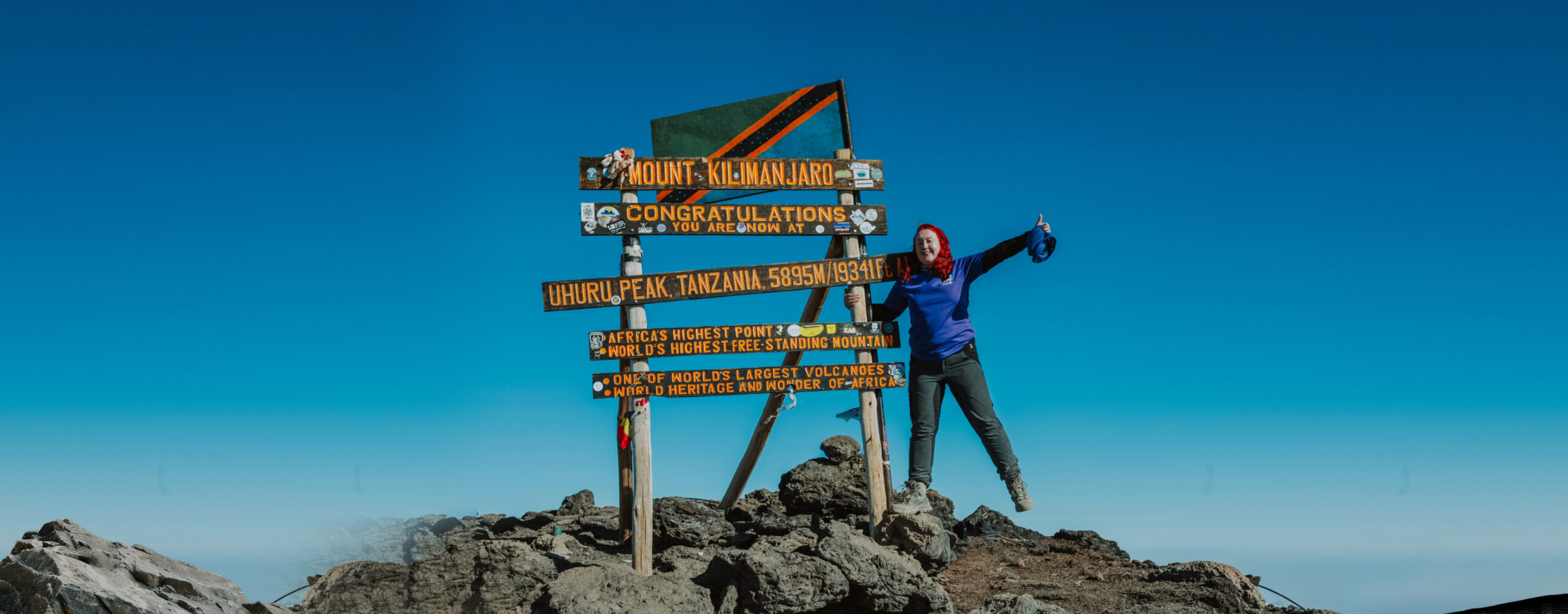 A woman Trekker standing proudly on top of Mount Kilimanjaro in Tanzania